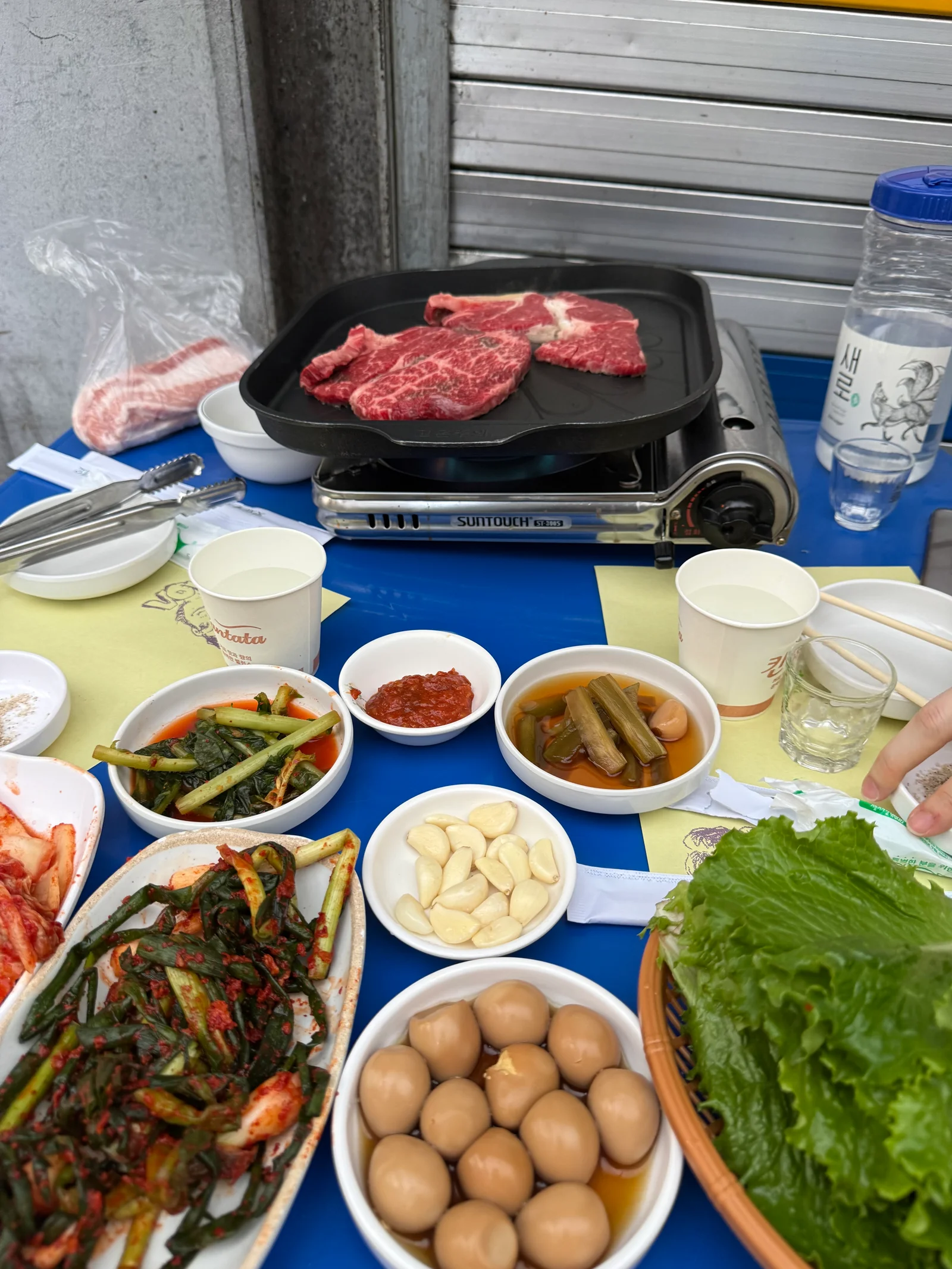 Outdoor Korean BBQ table at Moa Sikpum in Euljiro Seoul with marbled beef on grill and banchan