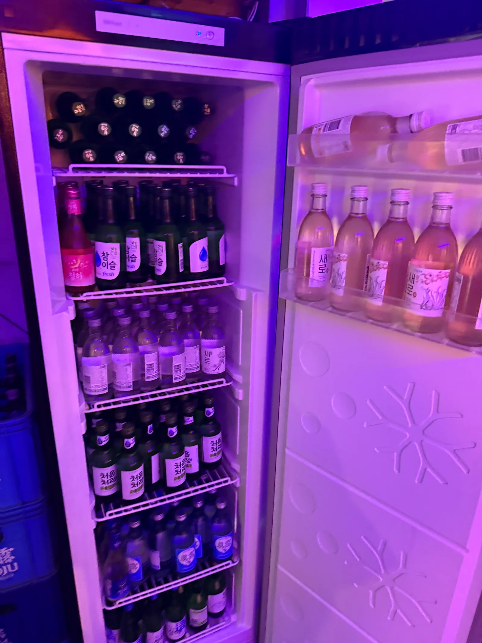 Neon-lit soju fridge stocked with Chamisul Chum-Churum and Saero bottles at Korean BBQ restaurant