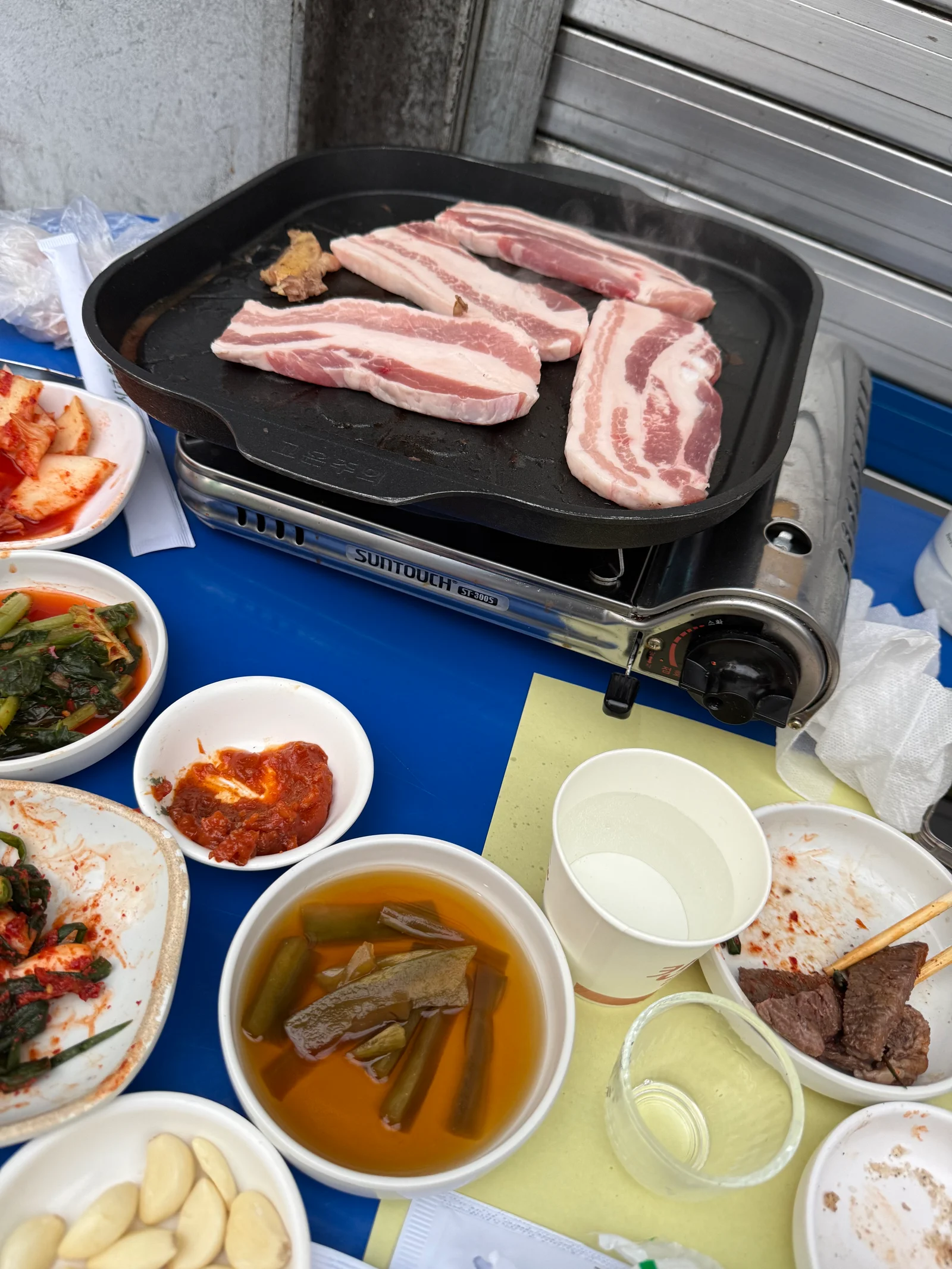 Thick-cut samgyeopsal pork belly grilling on cast iron at outdoor Euljiro yajang restaurant